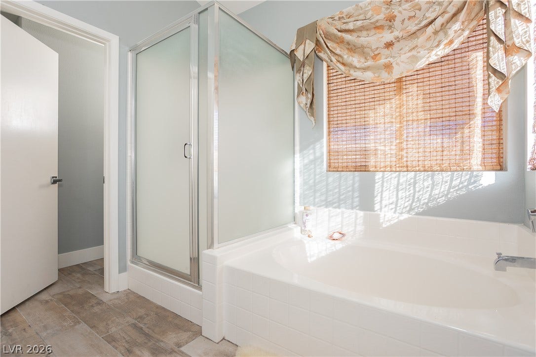 2421 Sunrise Springs Court, North Las Vegas, NV 89031 Natural light filters through the window above a built-in soaking tub and separate shower.