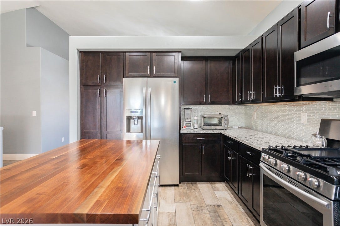 2421 Sunrise Springs Court, North Las Vegas, NV 89031 Rich dark cabinetry contrasts beautifully with a warm wood island and sleek stone countertops.