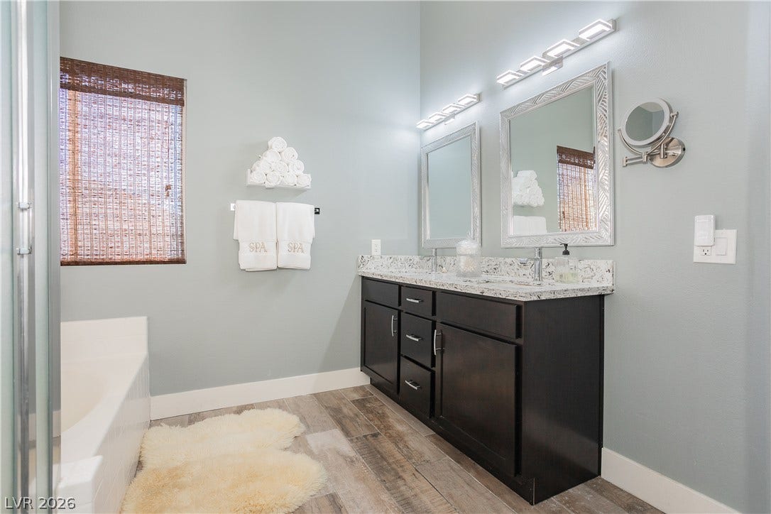 2421 Sunrise Springs Court, North Las Vegas, NV 89031 High ceilings and stone counters elevate this modern bathroom completed by rich wood-look tile flooring.