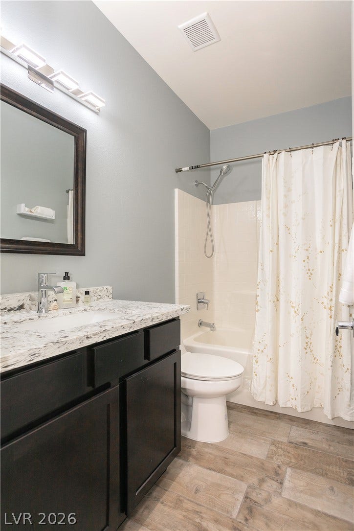 2421 Sunrise Springs Court, North Las Vegas, NV 89031 Gleaming stone countertops and wood-look tile flooring elevate this modern bathroom design.