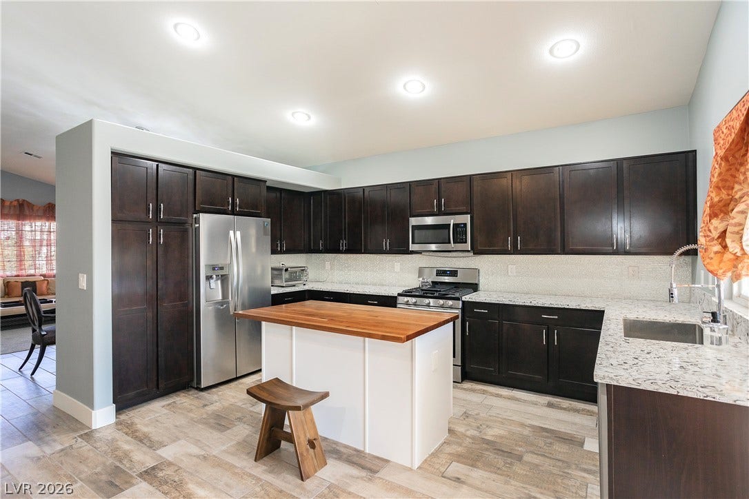 2421 Sunrise Springs Court, North Las Vegas, NV 89031 Rich dark cabinetry contrasts beautifully with granite countertops and a central wood-topped island.