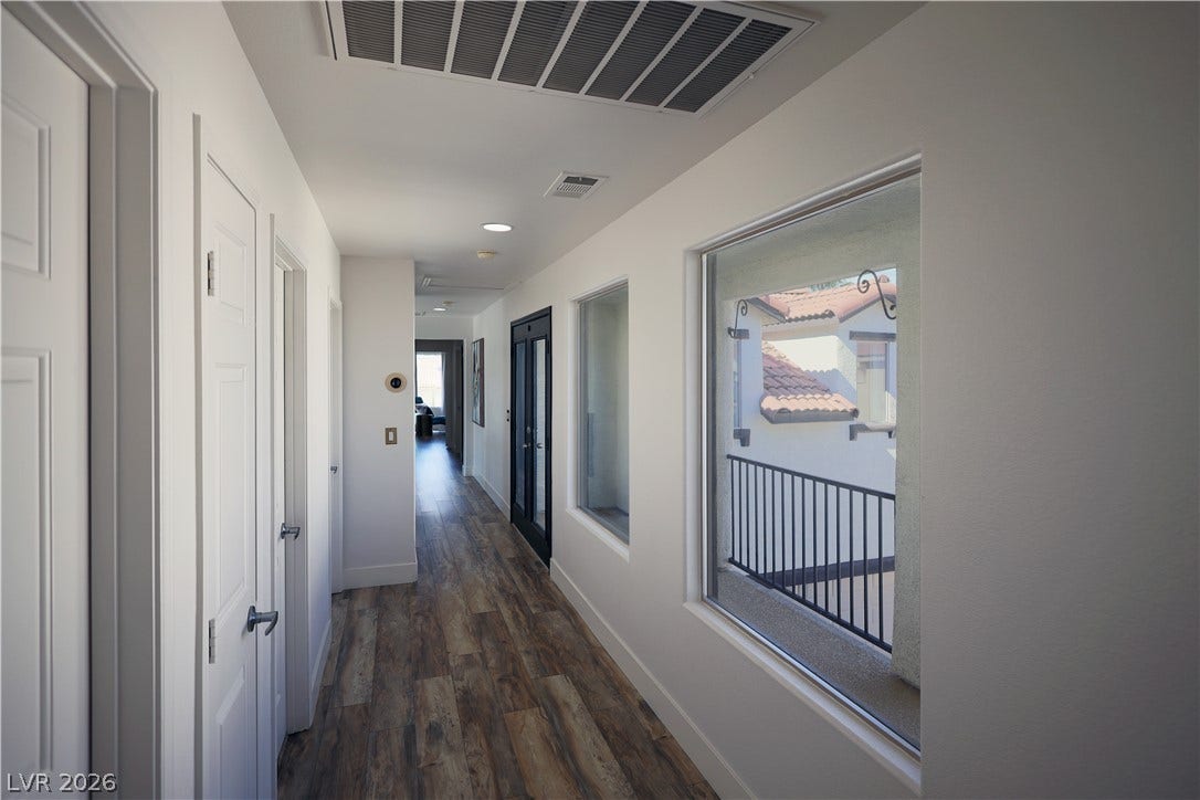 3018 Via Sarafina Drive, Henderson, NV 89052 Rich wood-look flooring and clean white walls line a bright corridor featuring large view windows.