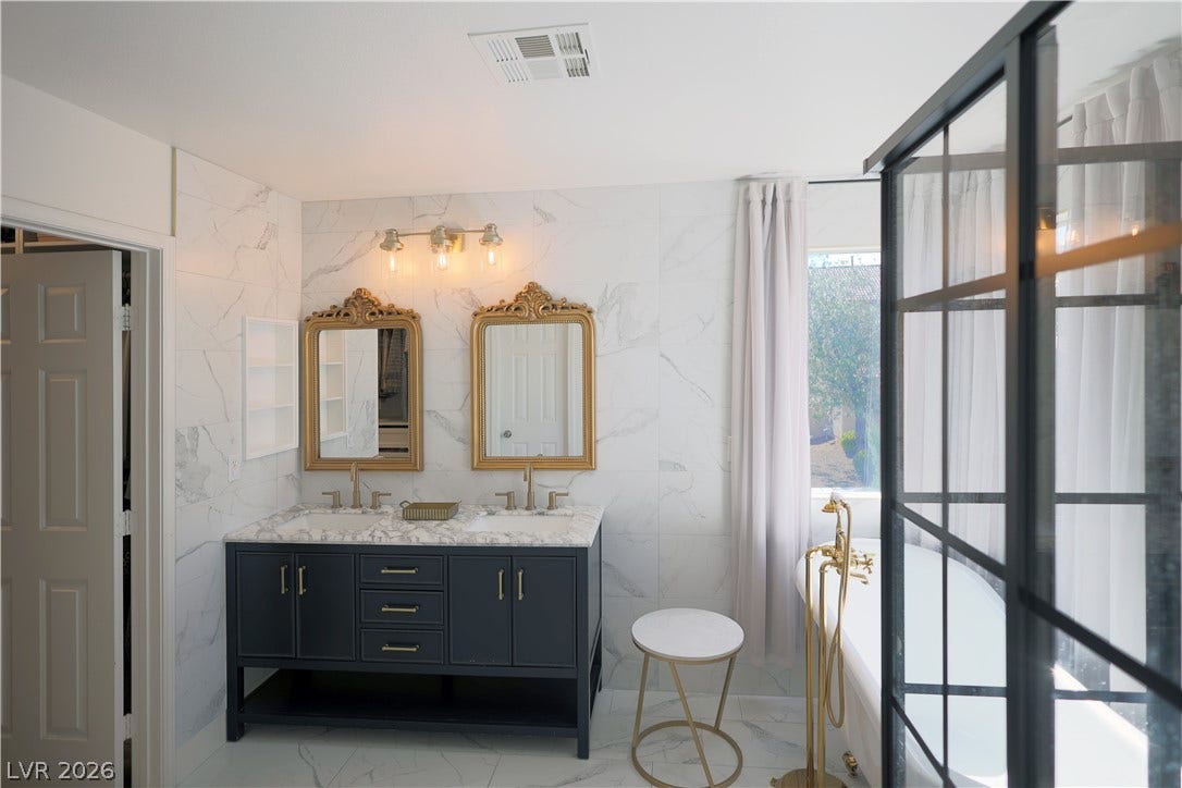 3018 Via Sarafina Drive, Henderson, NV 89052 Elegant marble tile surrounds a double vanity and freestanding soaking tub in this bathroom.