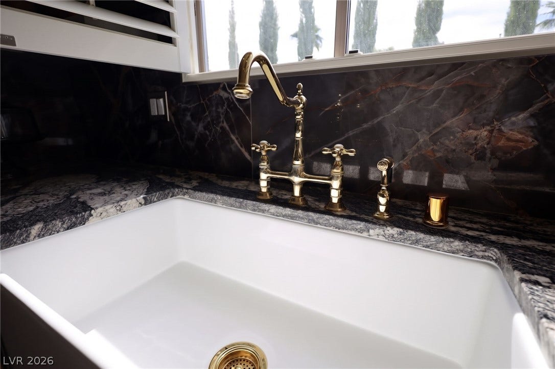 3018 Via Sarafina Drive, Henderson, NV 89052 Polished brass fixtures complement rich granite counters beneath a bright window.