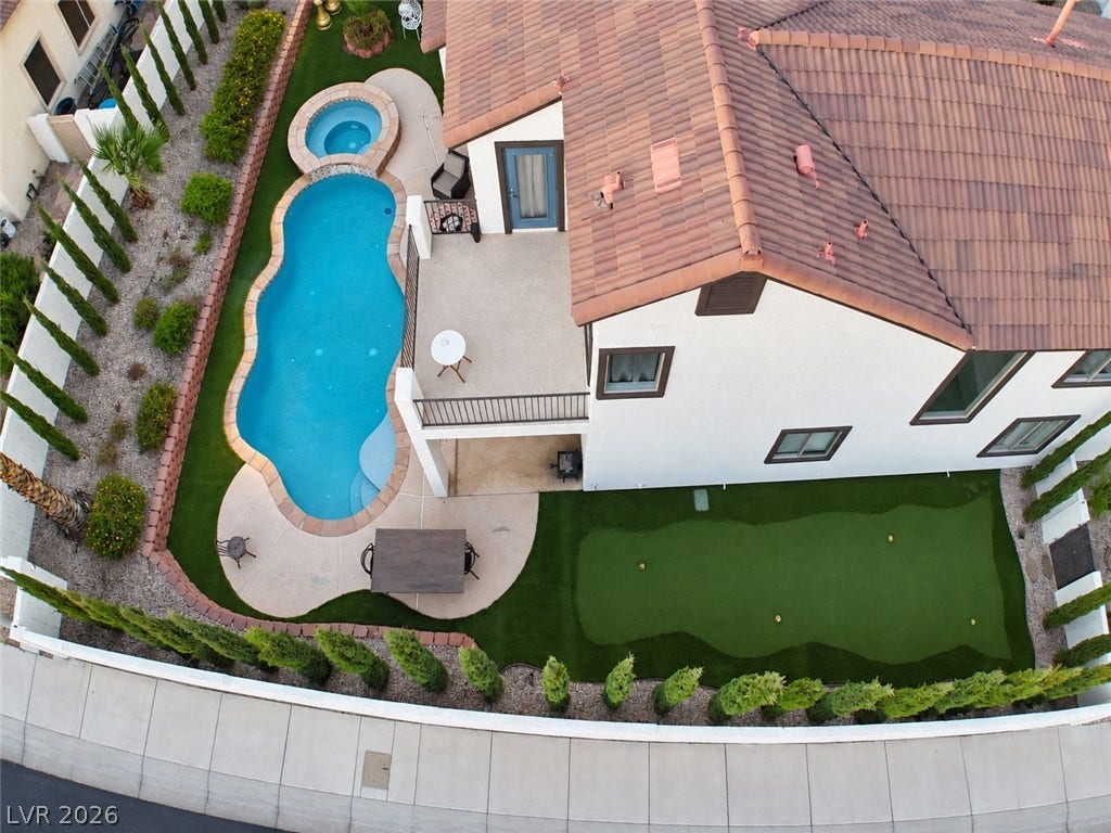 3018 Via Sarafina Drive, Henderson, NV 89052 A private backyard oasis features a glistening pool, elevated spa, and manicured putting green.