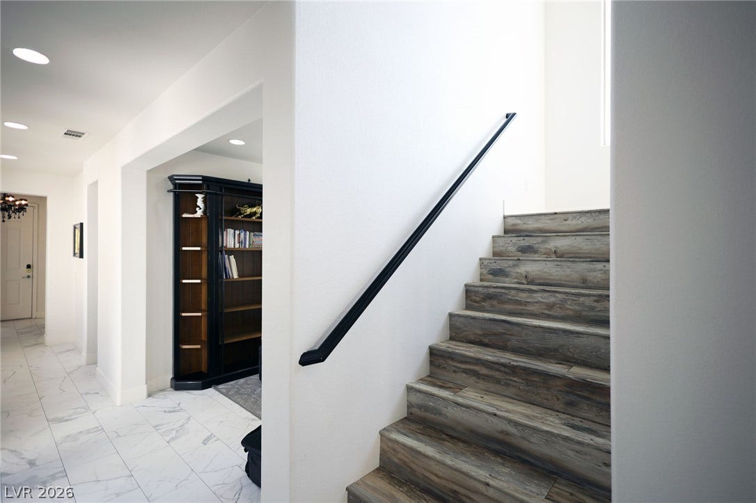 3018 Via Sarafina Drive, Henderson, NV 89052 A modern wooden staircase connects the levels adjacent to a bright tiled hallway.