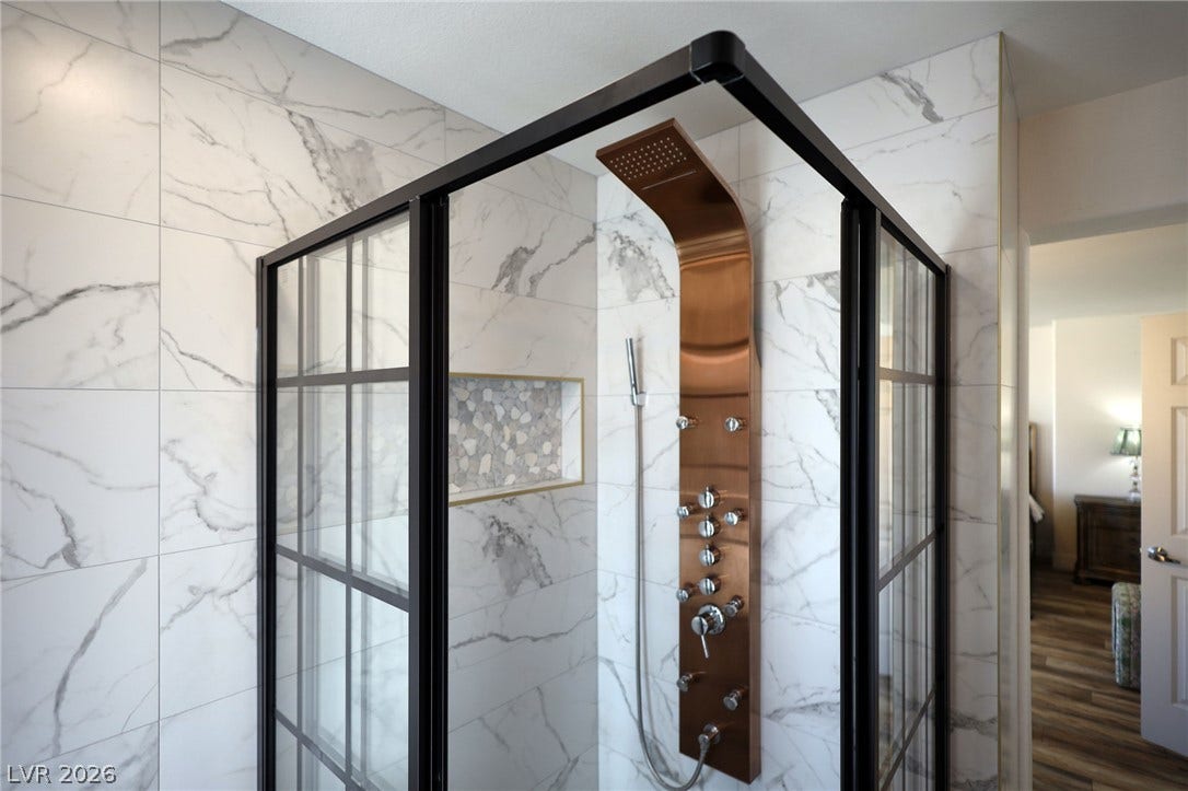 3018 Via Sarafina Drive, Henderson, NV 89052 A modern walk-in shower features elegant marble-patterned tile walls and premium bronze-finished plumbing fixtures.