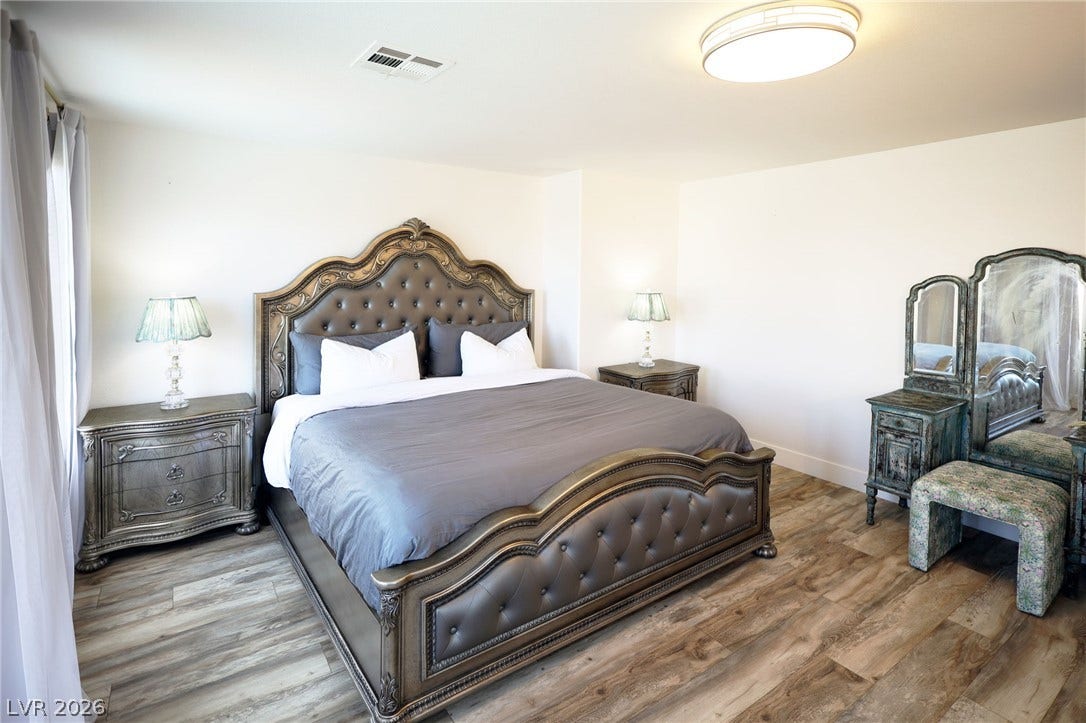 3018 Via Sarafina Drive, Henderson, NV 89052 Plank flooring and simple white walls frame a quiet and relaxing bedroom space.