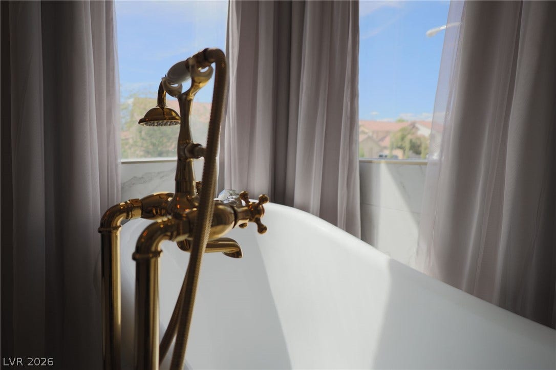3018 Via Sarafina Drive, Henderson, NV 89052 Sunlight streams across a classic soaking tub positioned beneath large, view-filled windows.