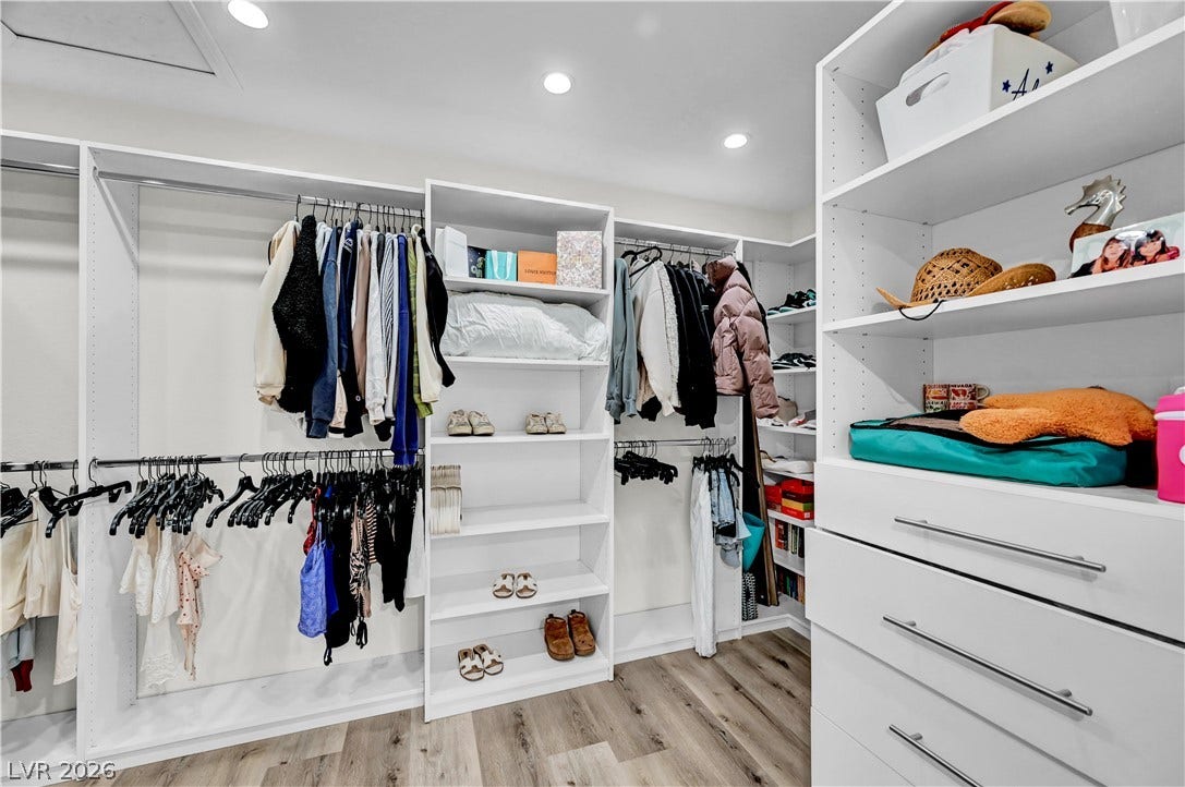4709 Amazing View Street, Las Vegas, NV 89129 An organized walk-in closet boasts custom shelving, built-in drawers, and recessed lighting over wood floors.