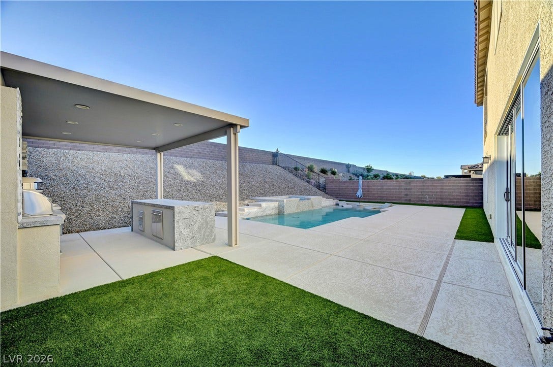 4709 Amazing View Street, Las Vegas, NV 89129 An inviting backyard oasis features a covered outdoor kitchen next to a sparkling pool.