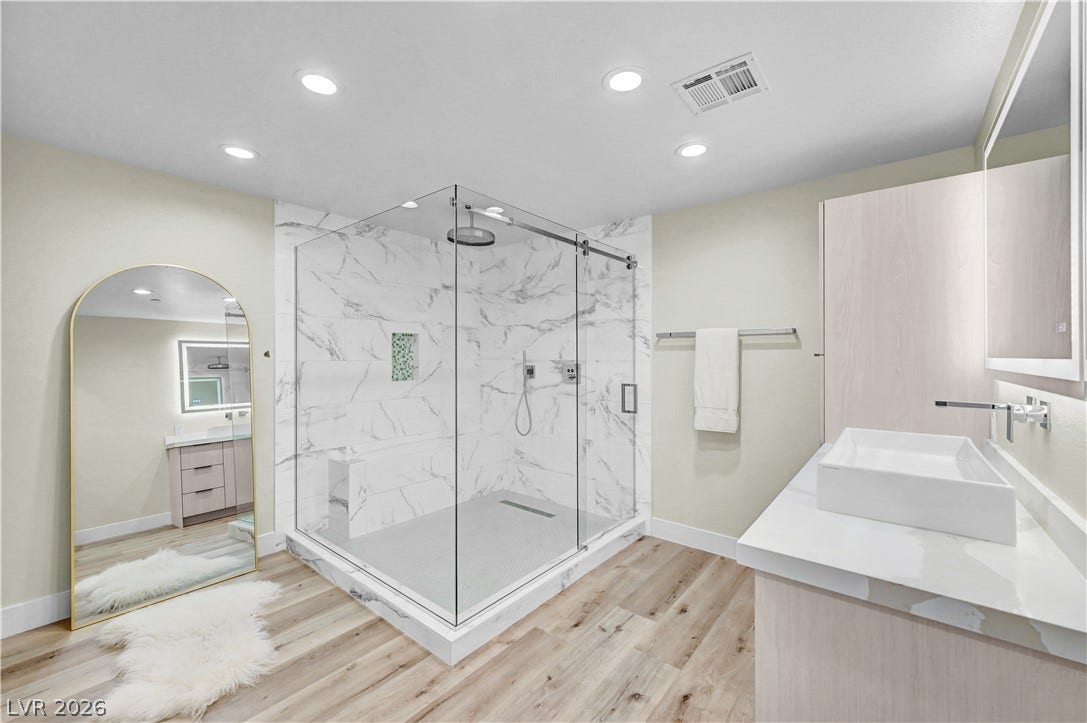 4709 Amazing View Street, Las Vegas, NV 89129 Elegant wide-plank wood flooring pairs beautifully with a glass-enclosed marble shower and sleek floating vanity.