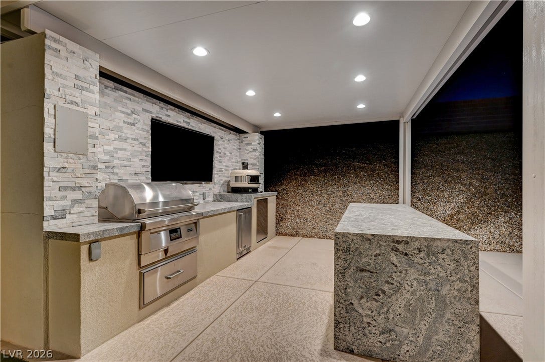 4709 Amazing View Street, Las Vegas, NV 89129 A stone-accented outdoor kitchen features built-in appliances and a waterfall island.