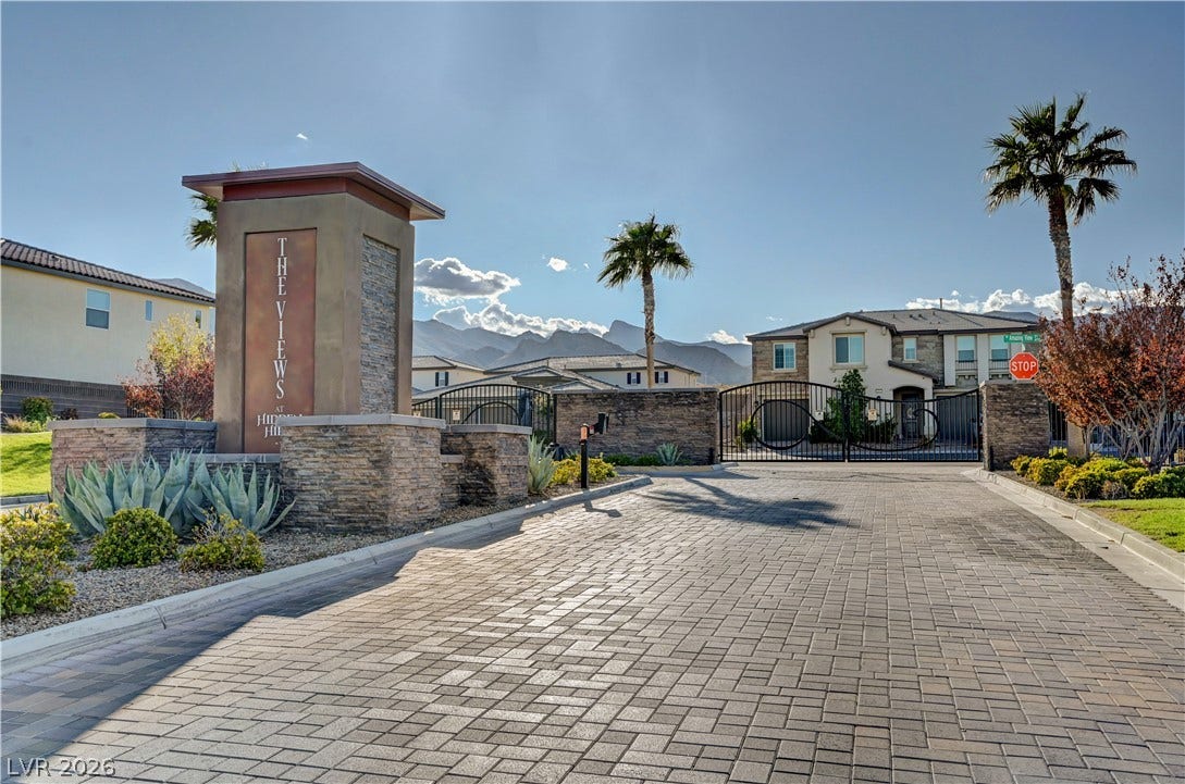 4709 Amazing View Street, Las Vegas, NV 89129 An elegant gated entry features a paved driveway and stone pillars set against mountain views.