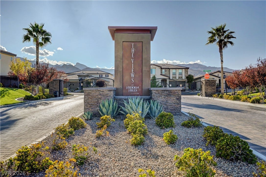 4709 Amazing View Street, Las Vegas, NV 89129 An inviting gated community entrance is framed by stone-accented pillars and manicured desert landscaping.