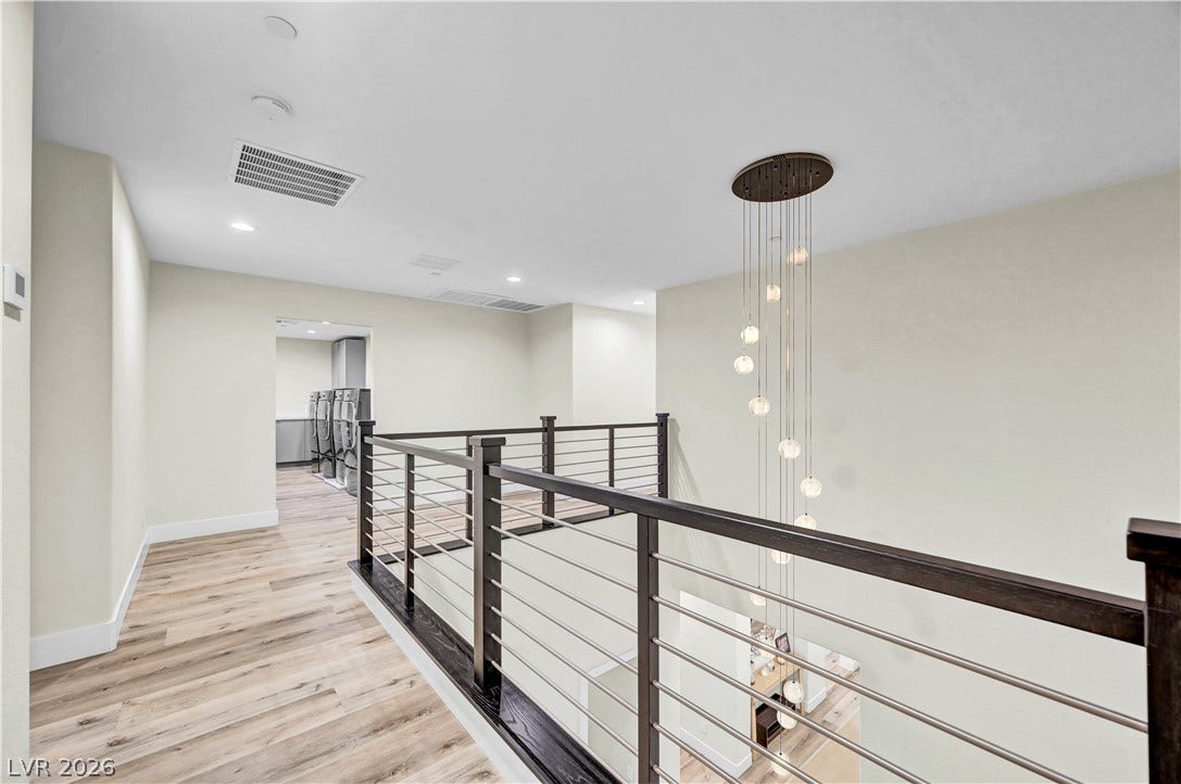 4709 Amazing View Street, Las Vegas, NV 89129 Clean lines and warm wood-style flooring define this modern upper-level hallway overlooking the stairs.