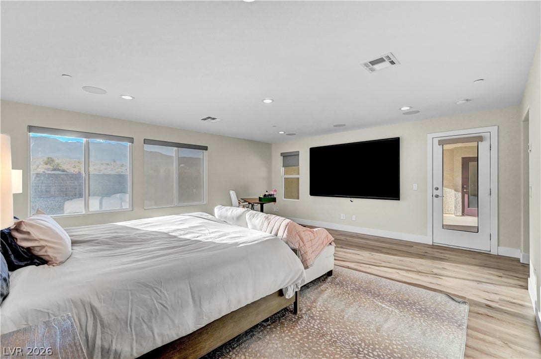4709 Amazing View Street, Las Vegas, NV 89129 Recessed lighting and wide-plank flooring define this modern bedroom with outdoor access.