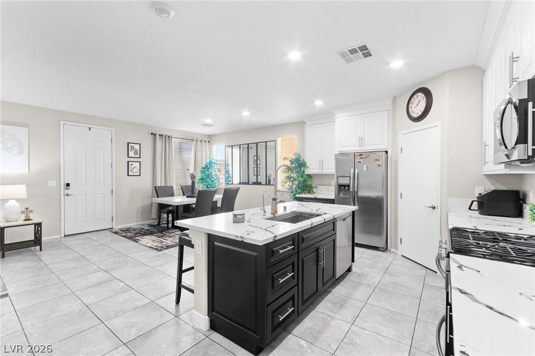 7224 Halo Falls Street, North Las Vegas, NV 89084 A sleek island kitchen featuring modern appliances and elegant countertops, seamlessly connected to a bright dining area.