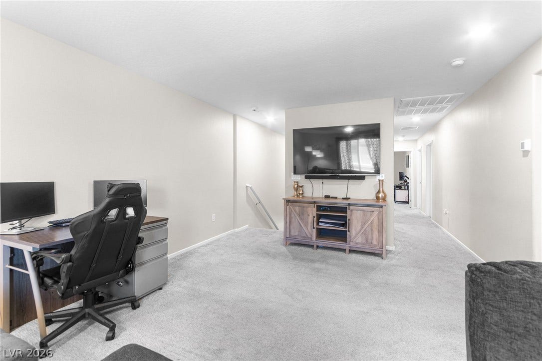 7224 Halo Falls Street, North Las Vegas, NV 89084 A well-lit lower-level den with plush carpeting offers versatile living and workspace options.