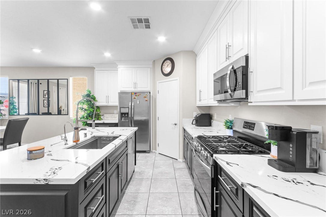 7224 Halo Falls Street, North Las Vegas, NV 89084 A well-appointed culinary space featuring sleek black and white cabinetry and gleaming stainless steel appliances.