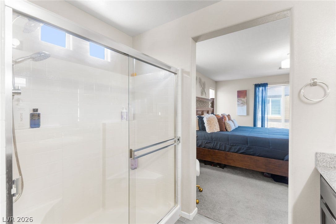 7224 Halo Falls Street, North Las Vegas, NV 89084 A sleek glass-enclosed shower adjoins a spacious bedroom with natural light.