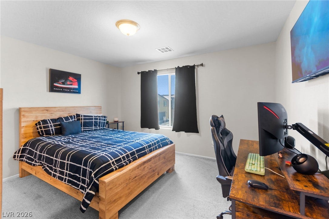 7224 Halo Falls Street, North Las Vegas, NV 89084 A well-lit bedroom features plush carpeting and a spacious window, creating a serene and comfortable retreat.