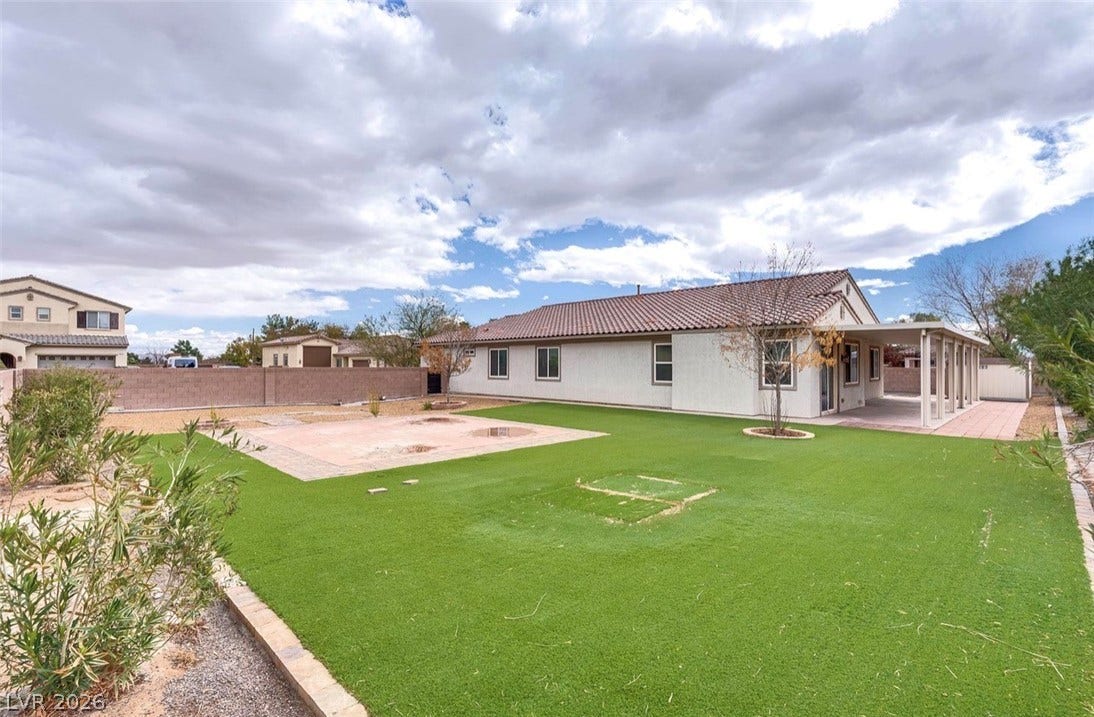 4709 Estate Ranch Street, North Las Vegas, NV 89031 A low-maintenance backyard oasis featuring synthetic turf and a shaded covered patio, ideal for outdoor leisure.