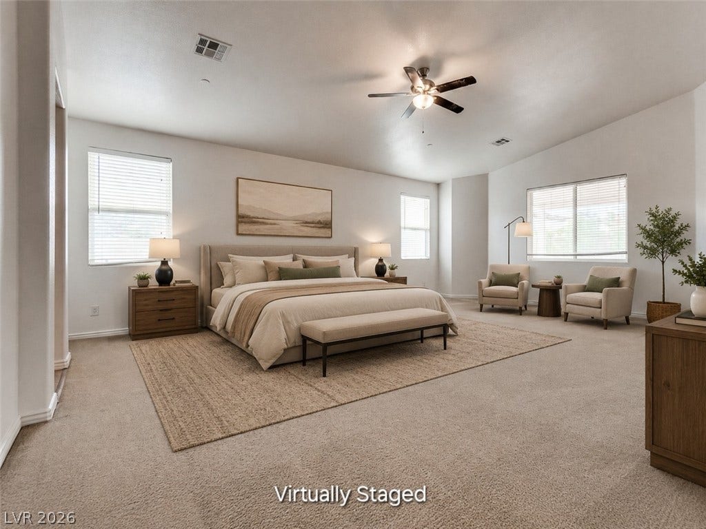 4709 Estate Ranch Street, North Las Vegas, NV 89031 A spacious primary bedroom features soft carpeting, ample natural light, and a ceiling fan for comfort.