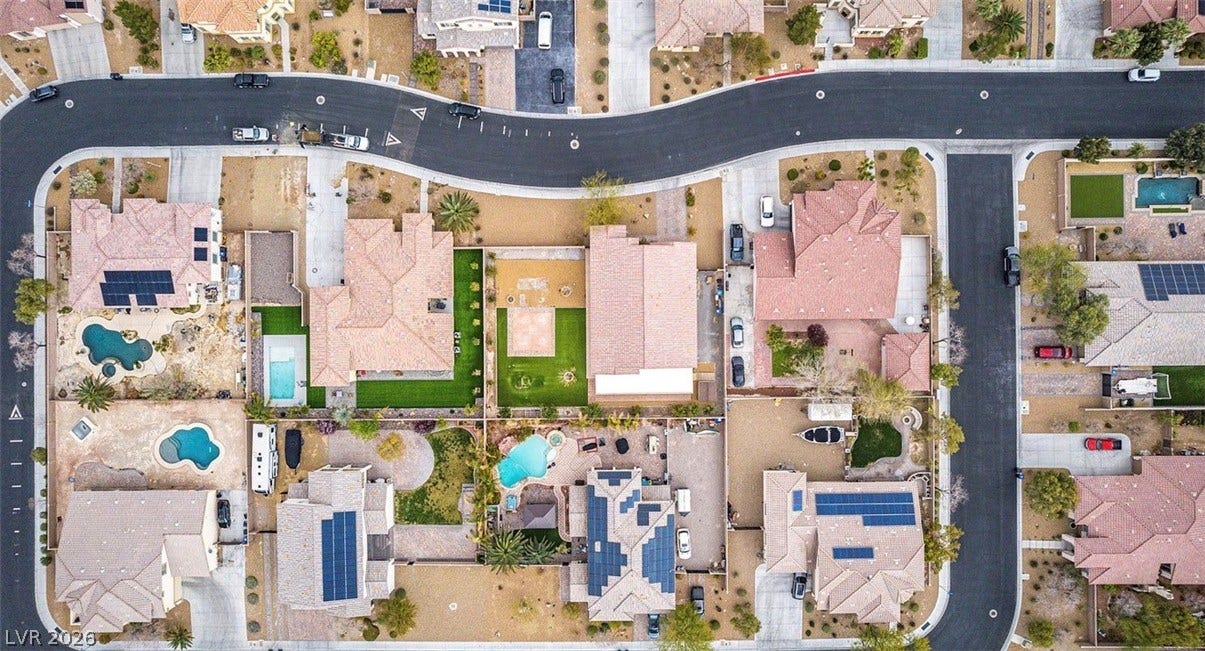 4709 Estate Ranch Street, North Las Vegas, NV 89031 An aerial perspective reveals a winding street and a neighborhood of residences, many featuring private pools and solar panels.