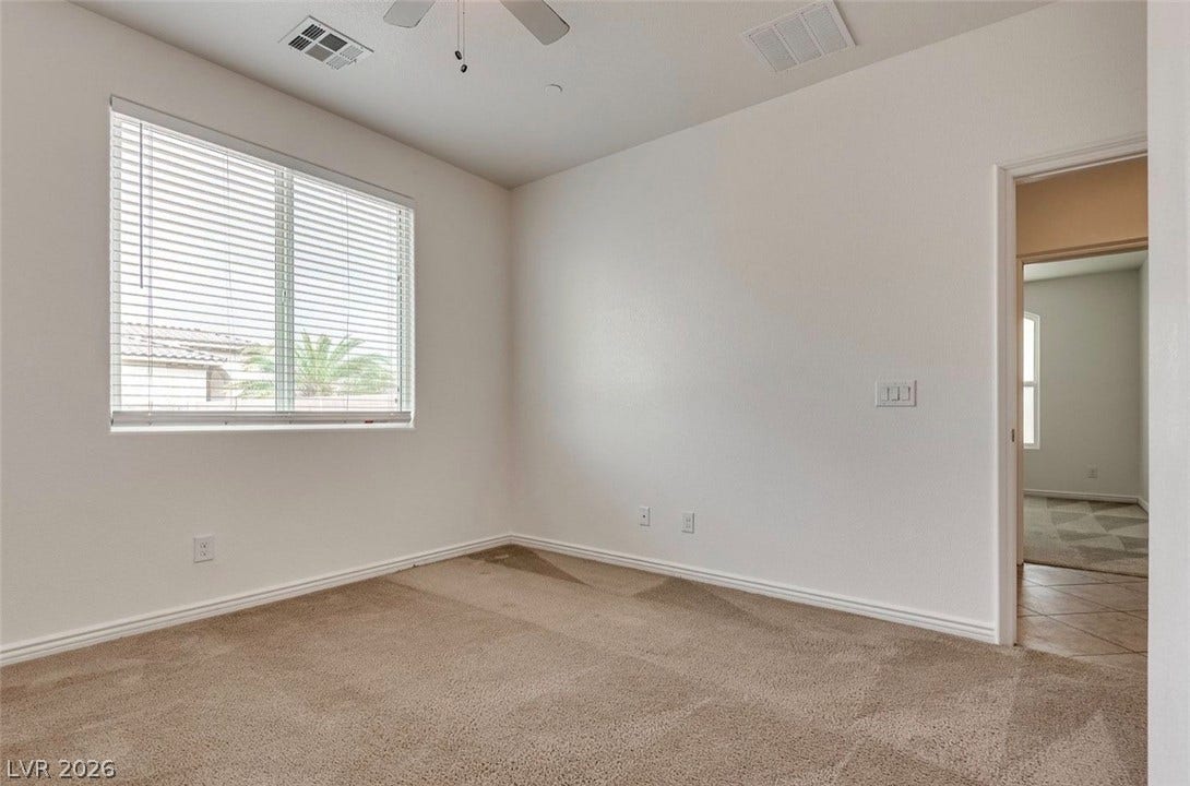 4709 Estate Ranch Street, North Las Vegas, NV 89031 A well-lit bedroom features plush carpet and ample natural light through a large window.
