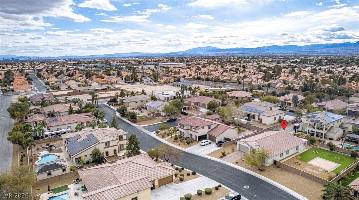 4709 Estate Ranch Street, North Las Vegas, NV 89031 An aerial perspective reveals a vibrant neighborhood with mountain views and residential rooftops.