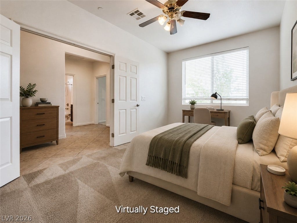 4709 Estate Ranch Street, North Las Vegas, NV 89031 A comfortable bedroom with a bright window, showcasing a ceiling fan and convenient access to a private bathroom.