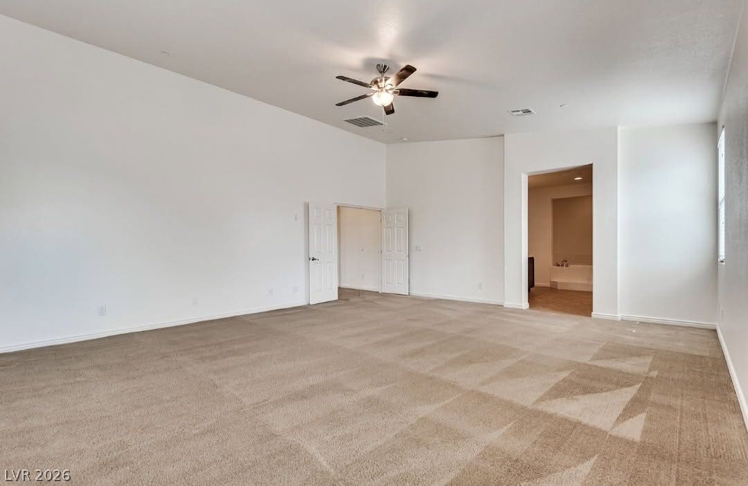 4709 Estate Ranch Street, North Las Vegas, NV 89031 A spacious primary bedroom features soft carpeting, a ceiling fan, and access to a luxurious primary bath.