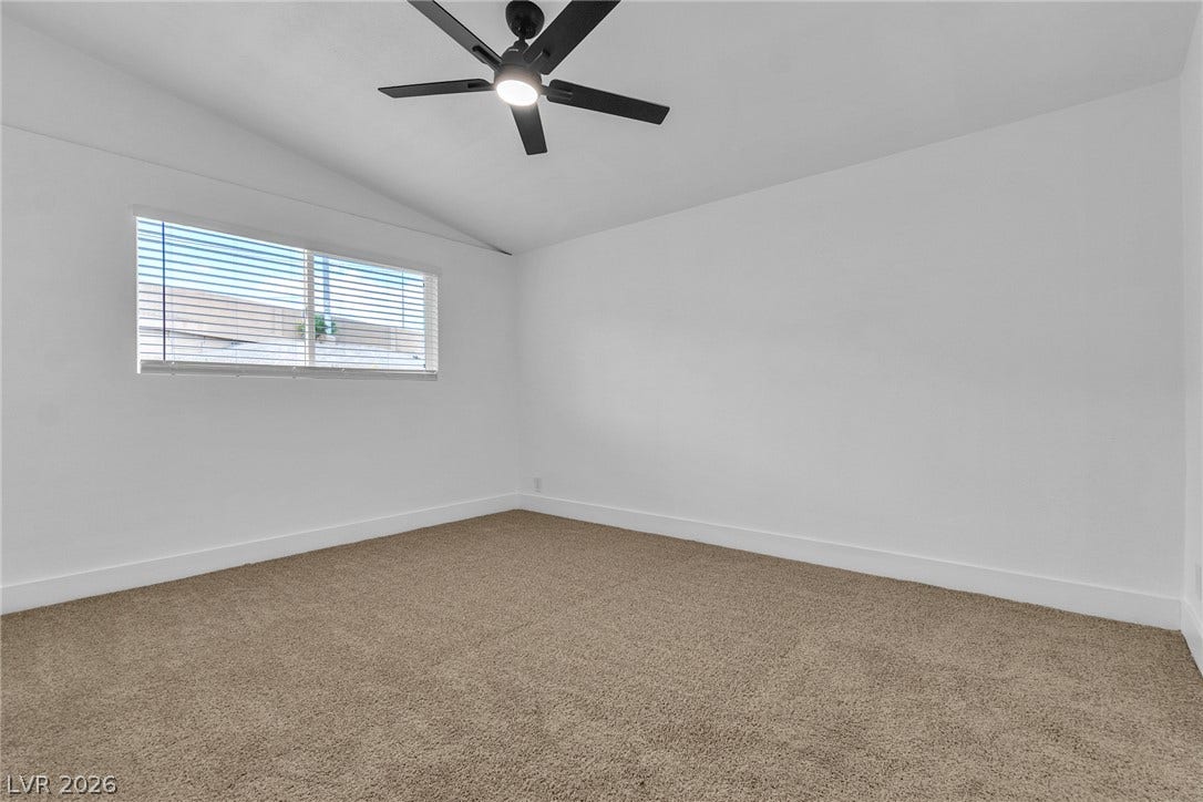 1604 Basswood Avenue, North Las Vegas, NV 89030 A spacious bedroom features soft carpeting, high vaulted ceilings, and a wide window.
