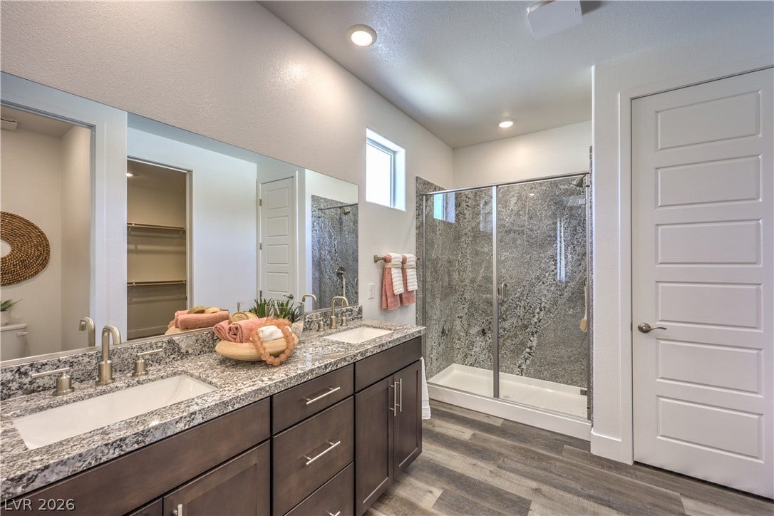 844 Kassie Lake Way, North Las Vegas, NV 89084 A contemporary bathroom features dual vanities under granite counters and a glass-enclosed shower. Representational only; Photo is of the 2660 Plan Model Home - NOT THE ACTUAL HOME FOR SALE *material/features/colors can vary from one community to the next & are subject to change*