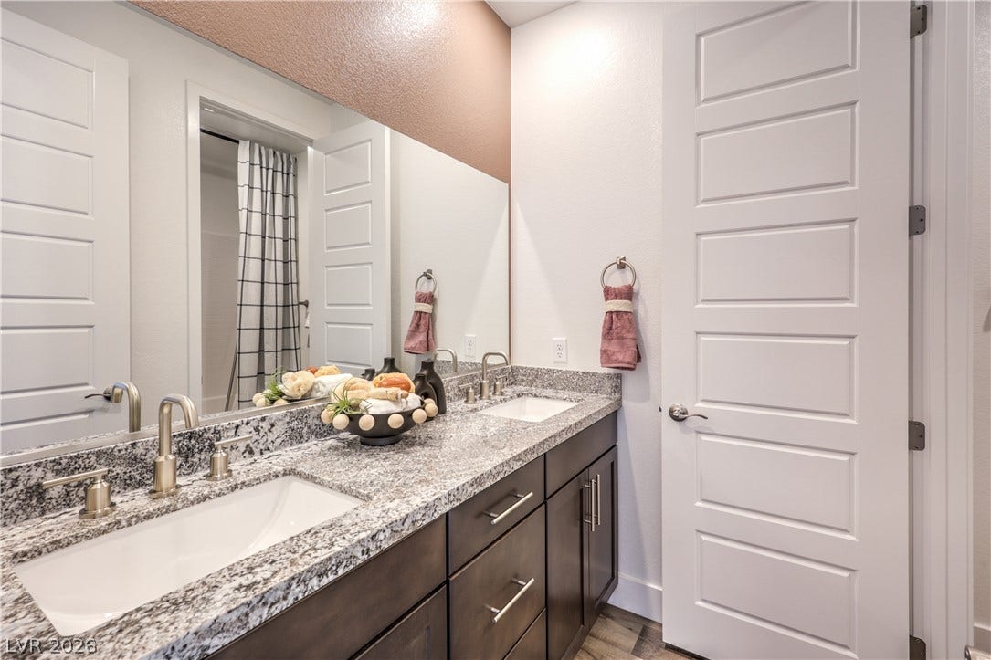 844 Kassie Lake Way, North Las Vegas, NV 89084 Double vanity sinks set in thick granite countertops elevate this modern bathroom space. Representational only; Photo is of the 2660 Plan Model Home - NOT THE ACTUAL HOME FOR SALE *material/features/colors can vary from one community to the next & are subject to change*