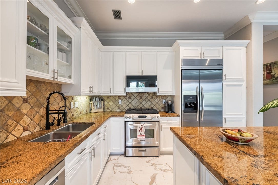 30 Via Vasari, #103, Henderson, NV 89011 Polished stone countertops pair elegantly with classic crown molding in this bright kitchen.