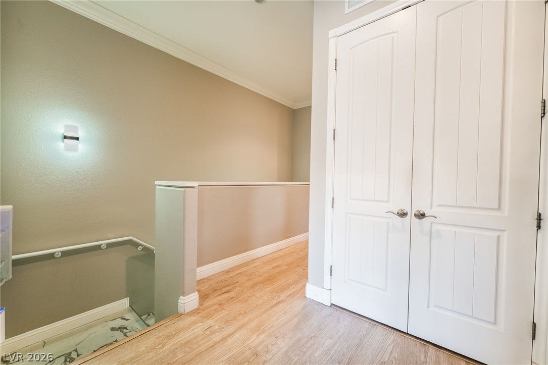 30 Via Vasari, #103, Henderson, NV 89011 Smooth wood floors flow past built-in storage to the descending staircase.