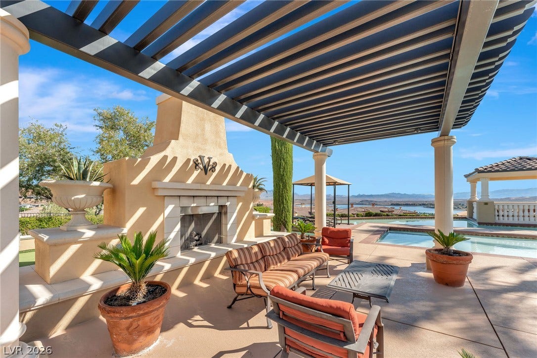 30 Via Vasari, #103, Henderson, NV 89011 A spacious stone patio features a built-in outdoor fireplace nestled under a classic overhead pergola.