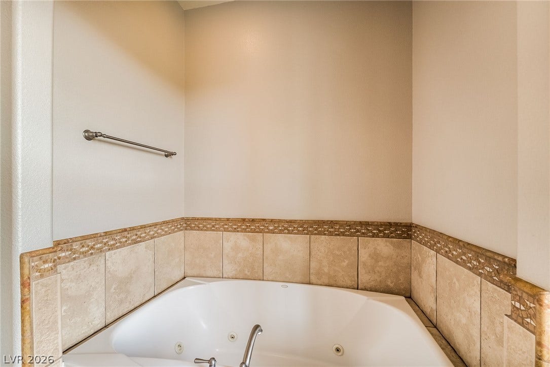 30 Via Vasari, #103, Henderson, NV 89011 Tiled wainscoting frames a deep soaking tub in this serene bathroom setting.