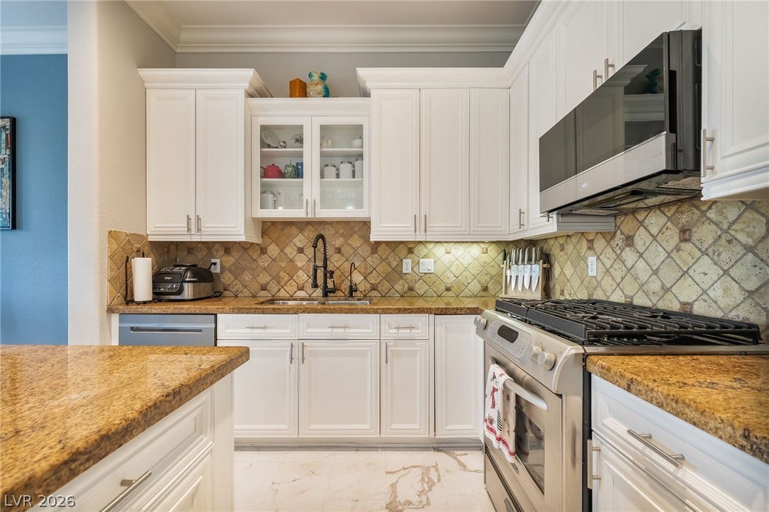 30 Via Vasari, #103, Henderson, NV 89011 Gleaming stone countertops and classic cabinetry elevate this bright kitchen space.