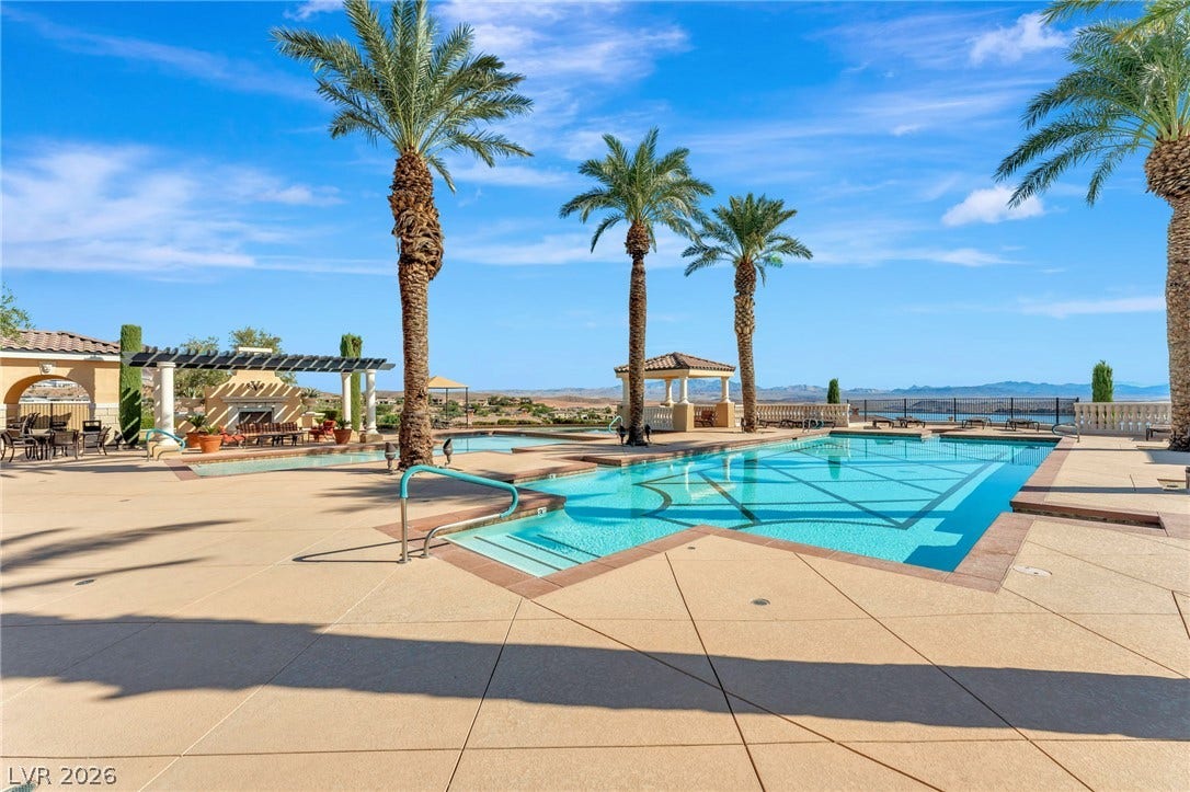 30 Via Vasari, #103, Henderson, NV 89011 An expansive outdoor pool deck framed by towering palm trees offers sweeping mountain views.
