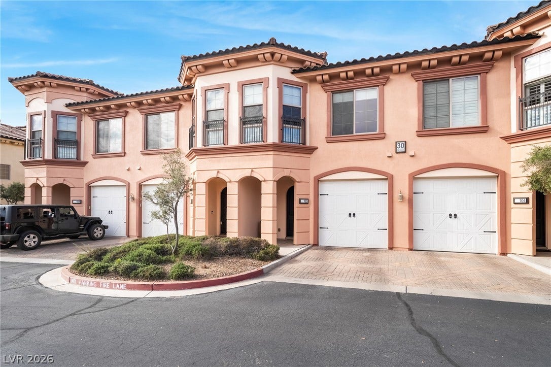 30 Via Vasari, #103, Henderson, NV 89011 Mediterranean architectural detailing frames this multi-level exterior featuring stucco walls and matching garage doors.