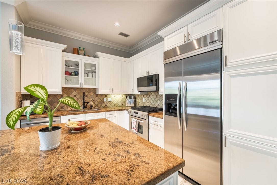 30 Via Vasari, #103, Henderson, NV 89011 Gleaming stone countertops and classic crown molding elevate this gourmet kitchen workspace.