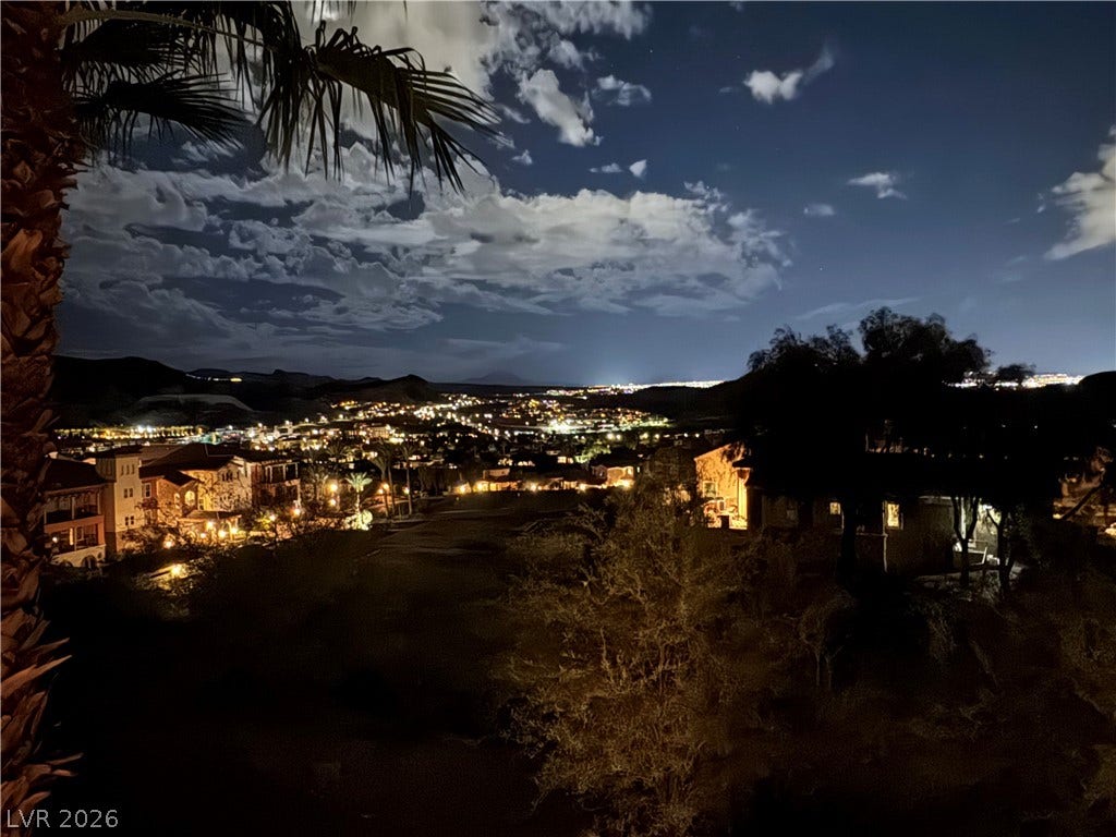 30 Via Vasari, #103, Henderson, NV 89011 Glimmering city lights stretch across the valley under a dramatic, cloud-filled night sky.