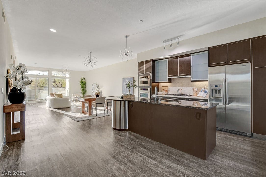 8925 W Flamingo Road, #111, Las Vegas, NV 89147 Rich wood flooring anchors this open-concept layout leading from the kitchen into the dining area.