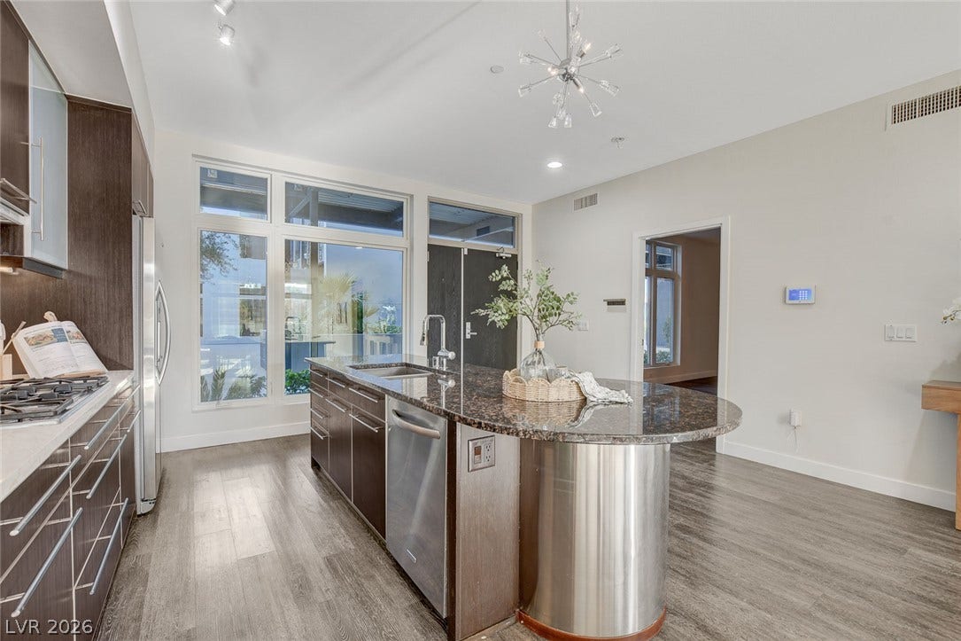 8925 W Flamingo Road, #111, Las Vegas, NV 89147 An expansive kitchen layout with high ceilings and a curved granite-topped island.