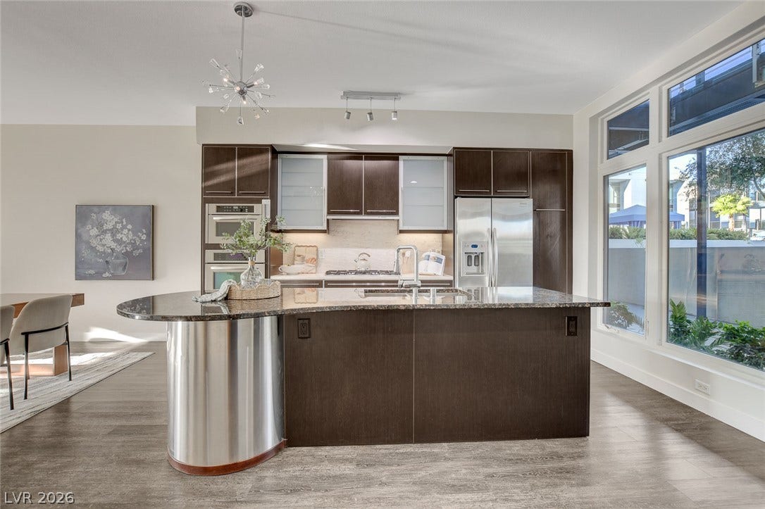 8925 W Flamingo Road, #111, Las Vegas, NV 89147 Rich wood cabinetry and a curved central island define this modern culinary workspace.