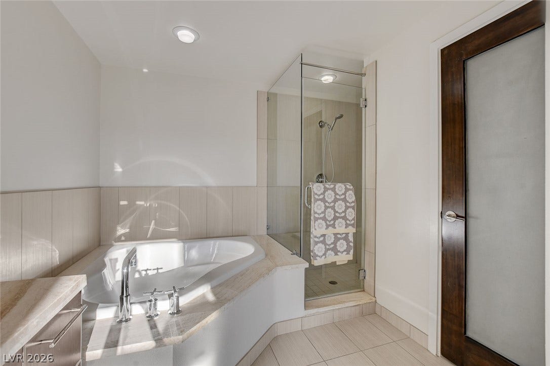8925 W Flamingo Road, #111, Las Vegas, NV 89147 Clean lines and stone finishes define this sleek bathroom featuring a soaking tub.