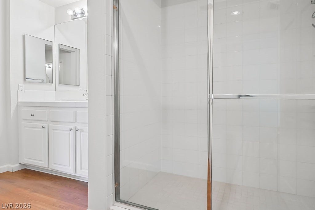 47 E Agate Avenue, #301, Las Vegas, NV 89123 White tiled walk-in shower sits adjacent to a classic vanity under bright vanity lights.
